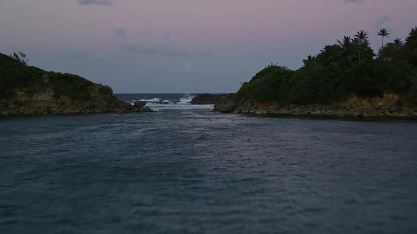 Aerial view of sea waves crashing on the coast of a tropical island