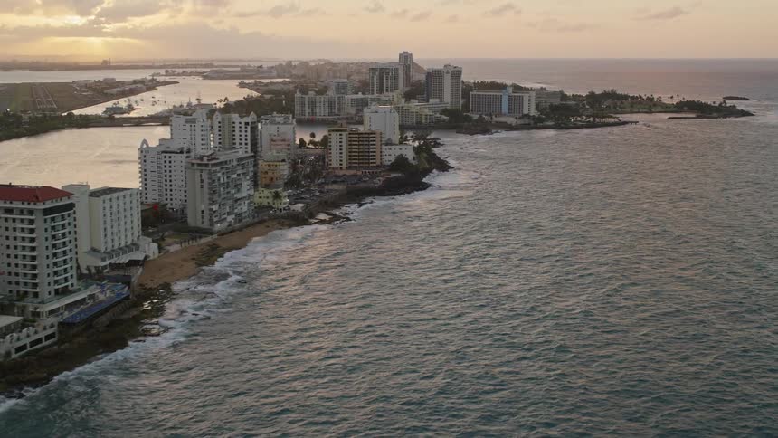 Aerial panorama of a hotel area in a seaside metropolis on a late afternoon with the sun on the horizon
