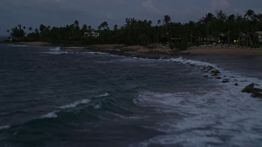 Panorama of a beach with rocks and tropical vegetation on a cloudy day at dawn