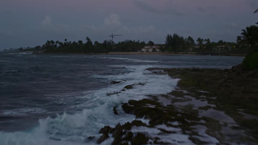 Aerial panorama of the sea at the edge of a tropical island with houses on a morning with a purple sky