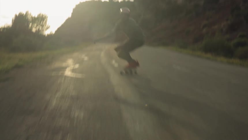 A skateboarder rides on a rural road