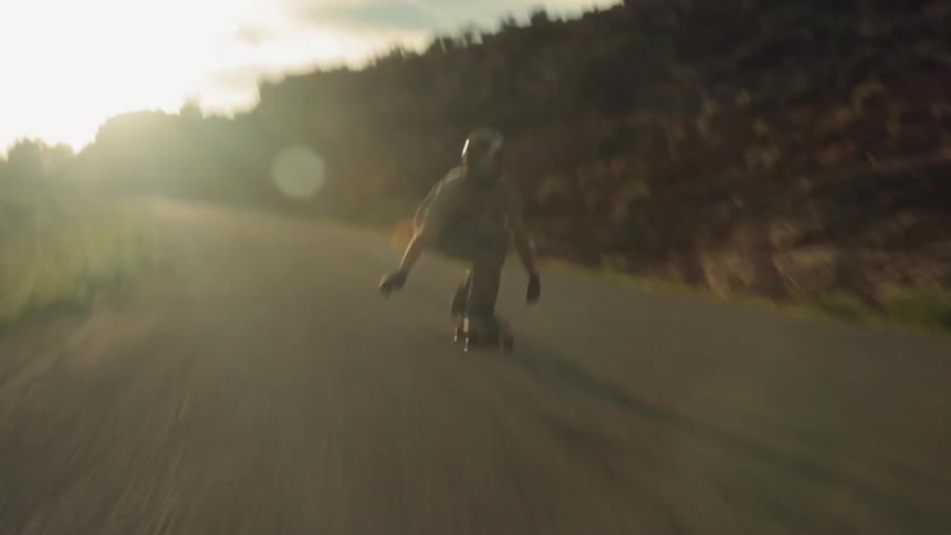 A skateboarder rides down a mountain road at a fast speed