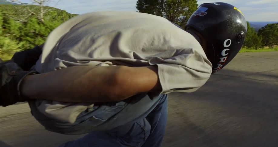 A man in a helmet skateboards down the road