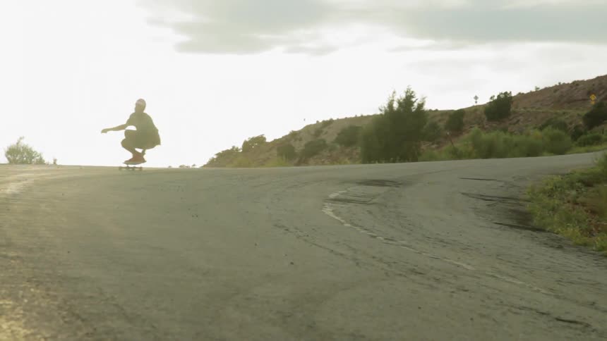 Man skateboarding very quickly down a curved hill