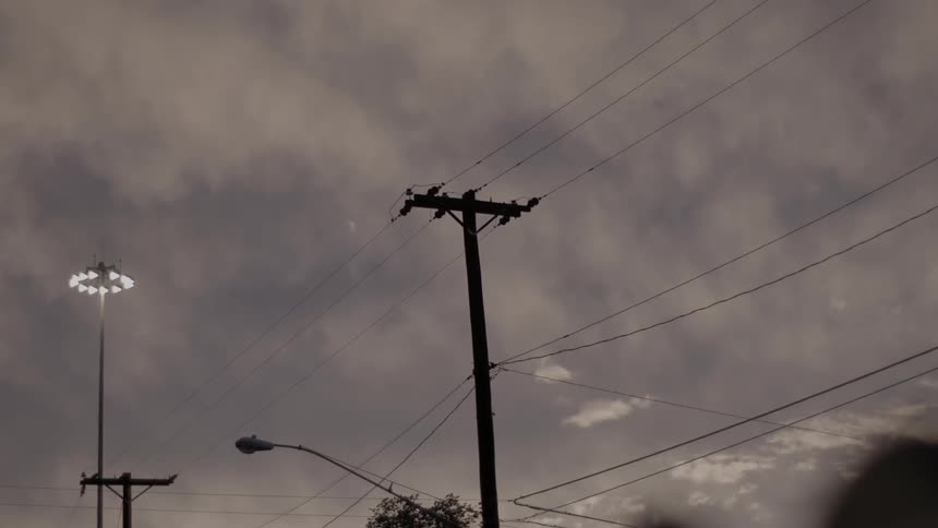 Power lines and a large light on a cloudy day