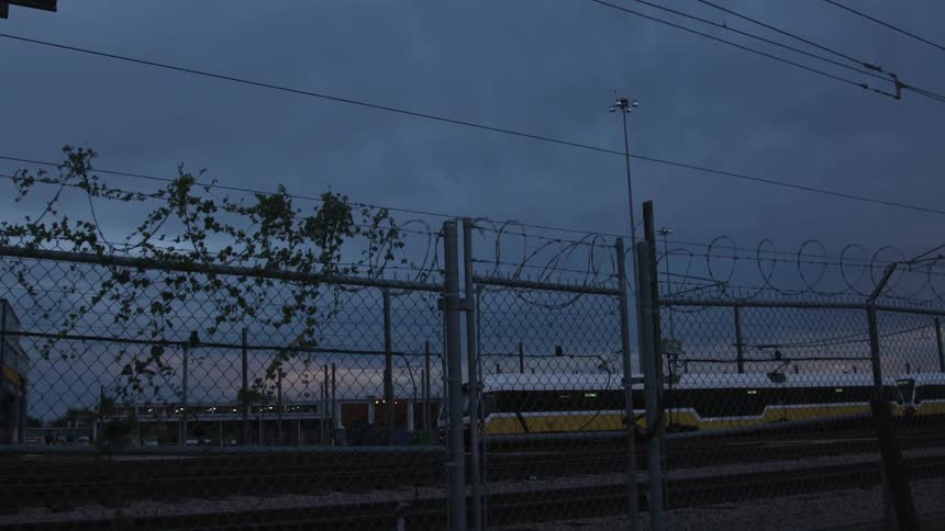 The sun is setting behind this barb wire fence