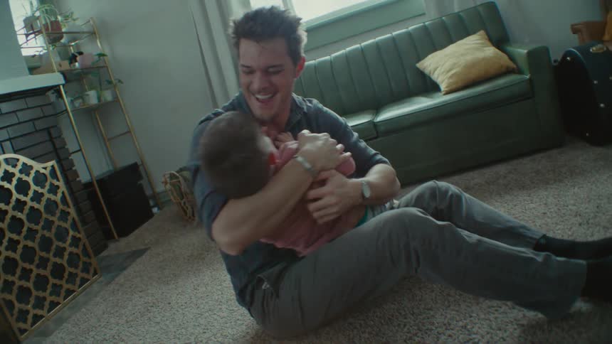 A father and son play together on the floor of their living room