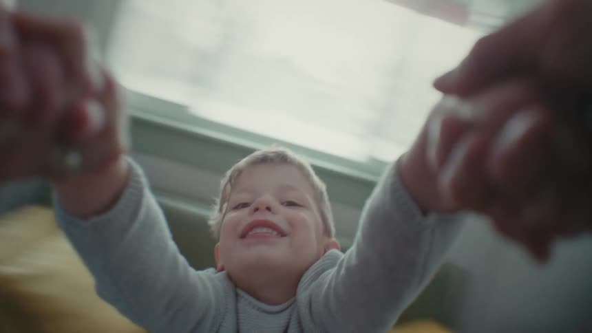 A young boy smiles as he gets swung by his arms by his father