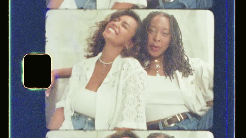 Two black women sit and pose while wearing similar outfits