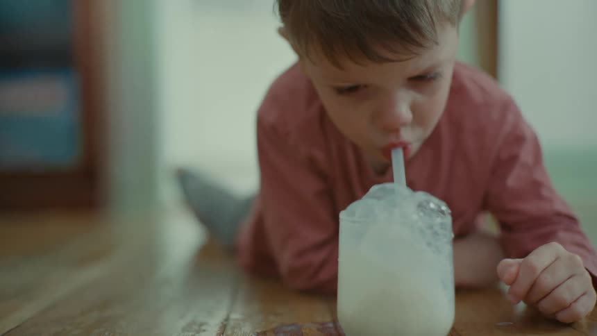 A child blowing bubbles in milk