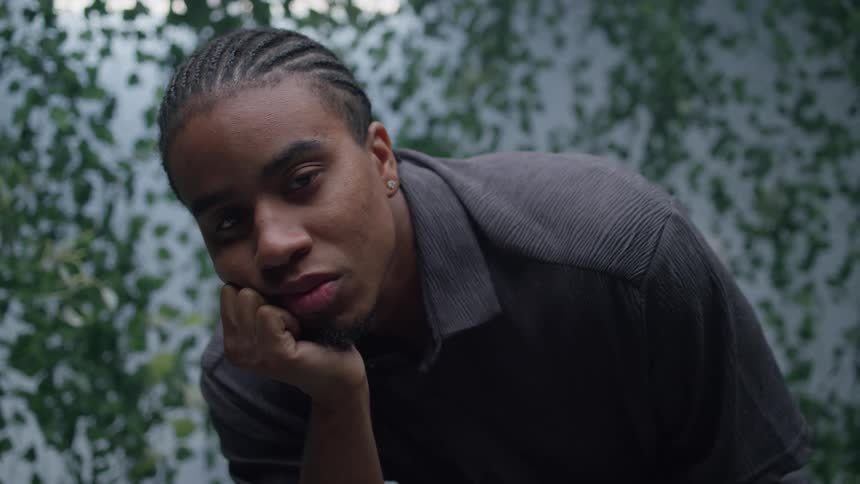 A black man rests his face on his hand