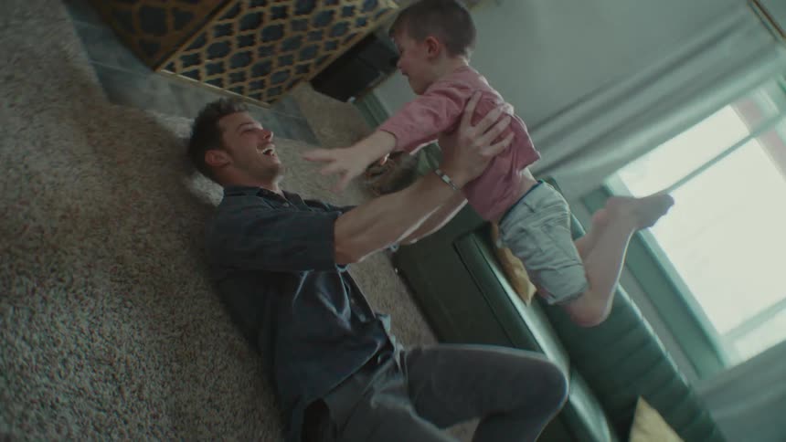 A father and son playing indoors on a sunny day
