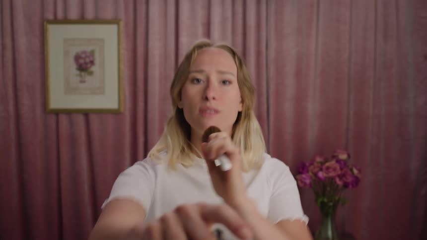 Blonde woman sings pretending a makeup brush is a microphone
