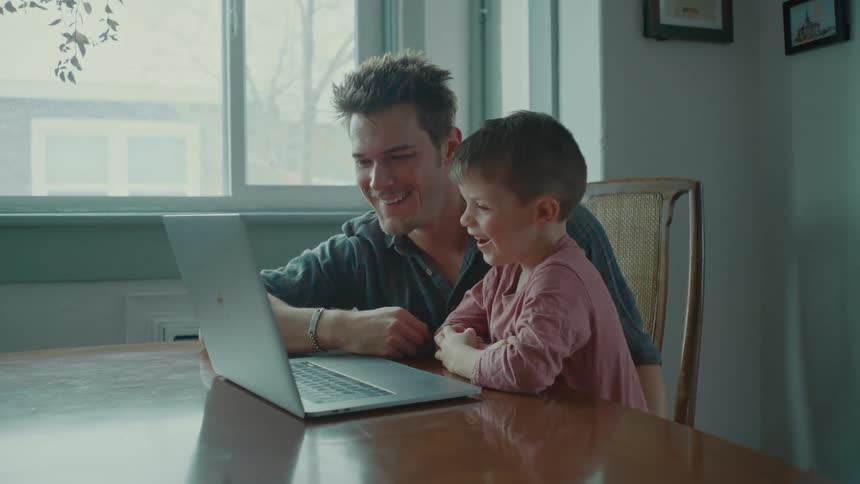 A man and a child use a laptop