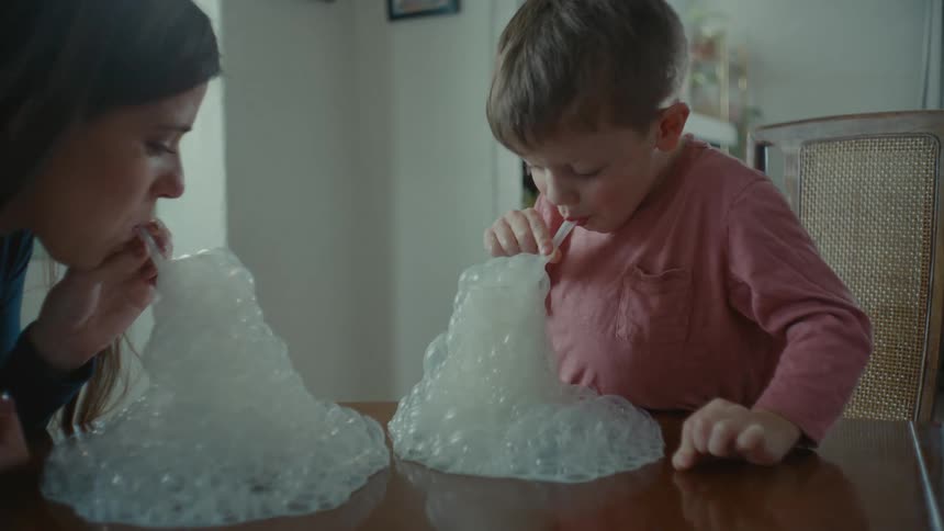 A mother and son bubbles from a glass