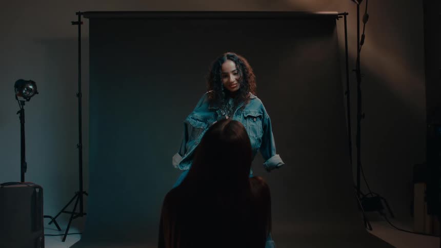 A black woman models clothing while being filmed