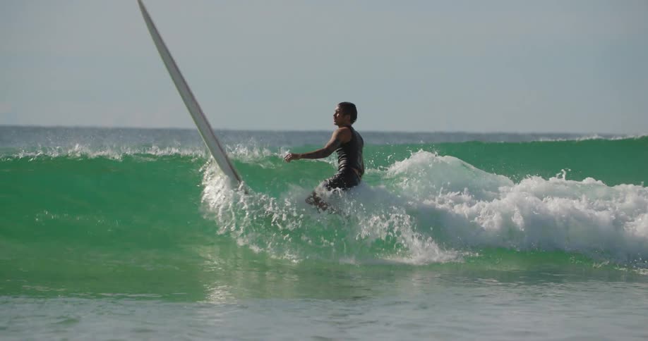 A man surfs a wave and falls off the board