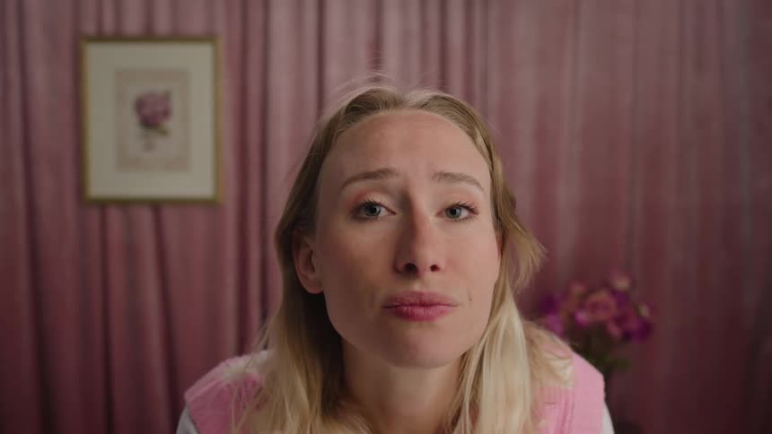 A woman with blonde hair checks her appearance in a mirror