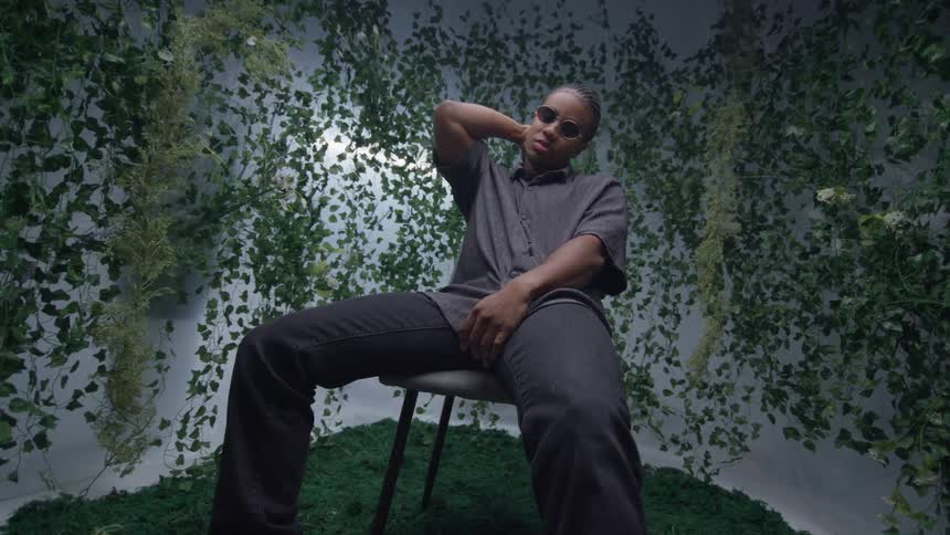 A black man with sunglasses sits in a chair
