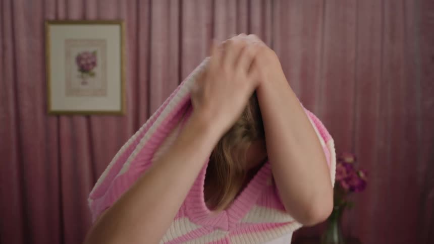 A woman puts on a sweater and smiles