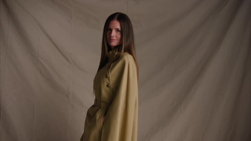 Young woman modeling with a coat in a studio