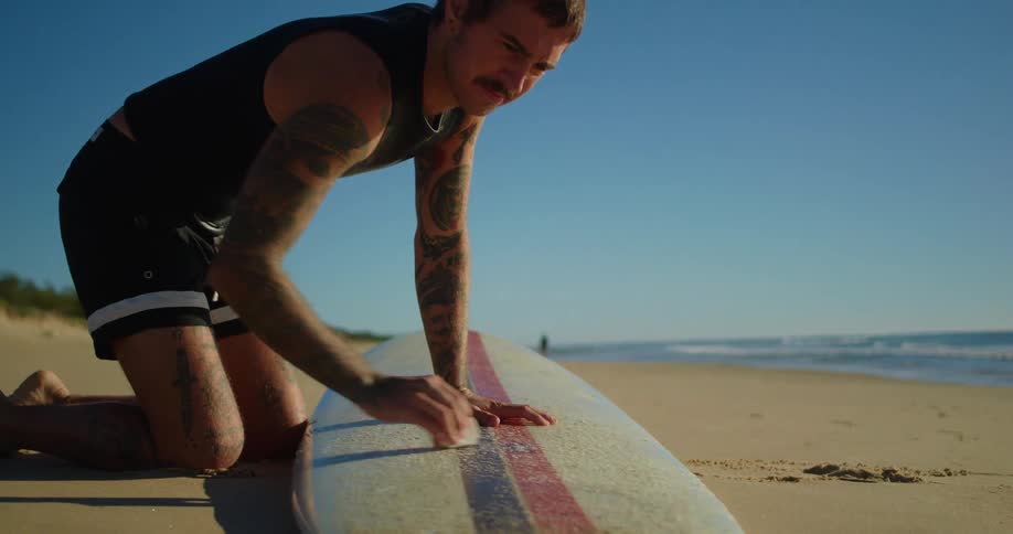 A man is polishing his surfboard