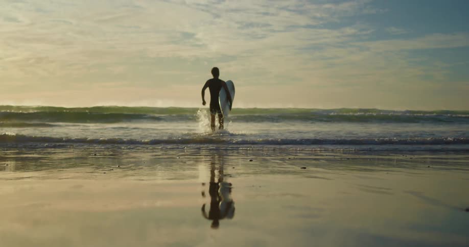 A man carries a surfboard and runs away from the beach to catch a wave