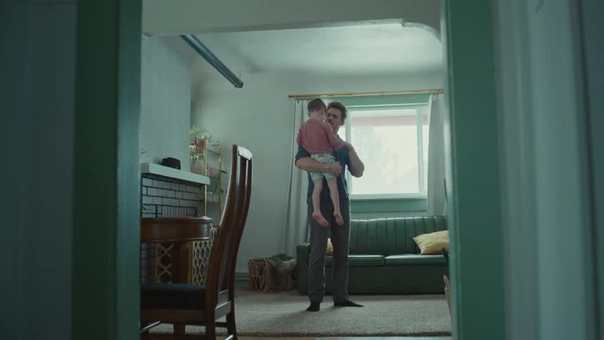 A man holds his son in a living room