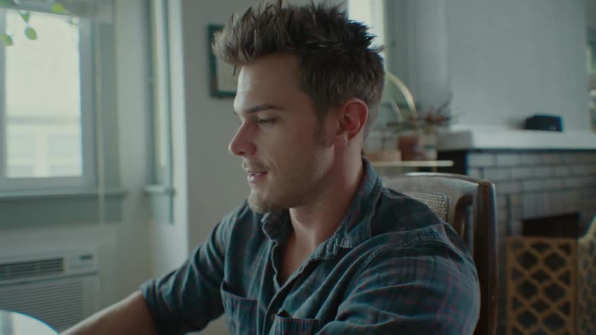Portrait of a man sitting answering the phone and his son passing by playing in the background