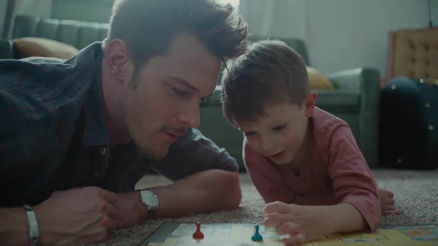 Father lying on the floor with his little son playing a board game