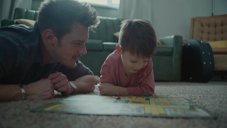 A man and a boy play a game on a living room floor