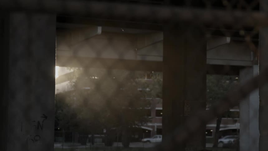 Looking through a chain link fence at a busy city street