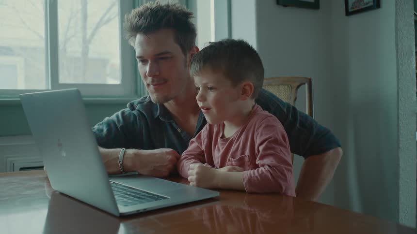 Father sitting with his son facing the laptop