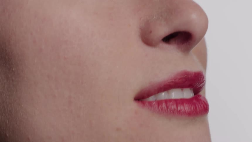 Closeup on the face of a woman wearing makeup and red lipstick