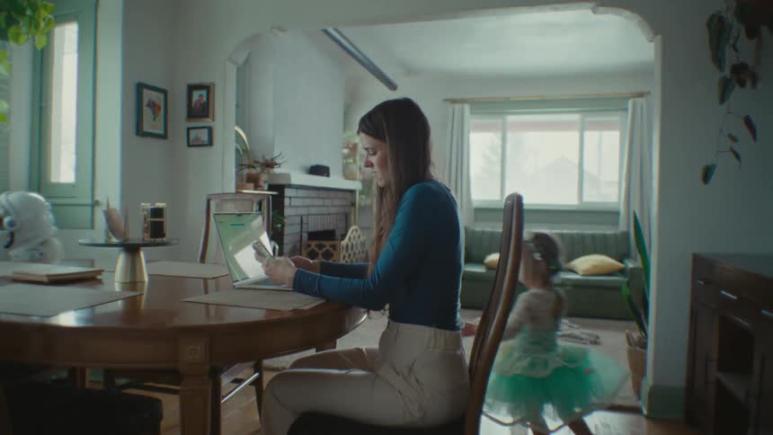 Mother working from home while her children play around the house