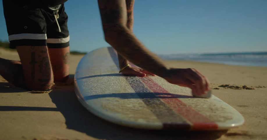 Man applying paraffin to his surfboard