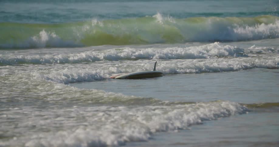 Surfboard being carried by the tide of the sea
