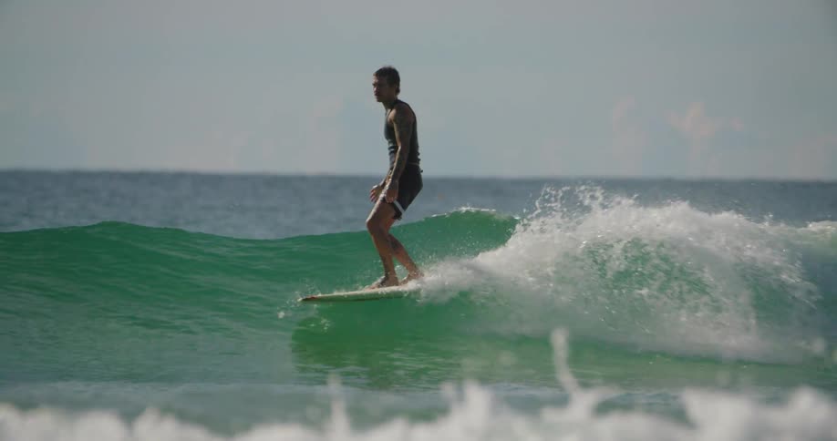 Man surfing a wave in a greenish sea during the day