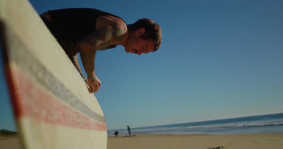 Man applying paraffin to his surfboard