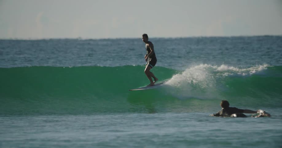 Surfer stands up on board to ride wave before falling