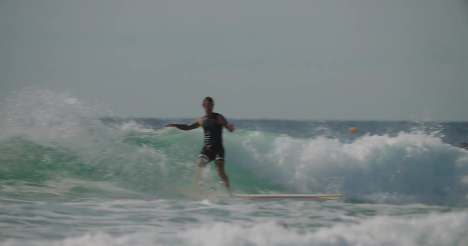 A man raises his arms as he surfs