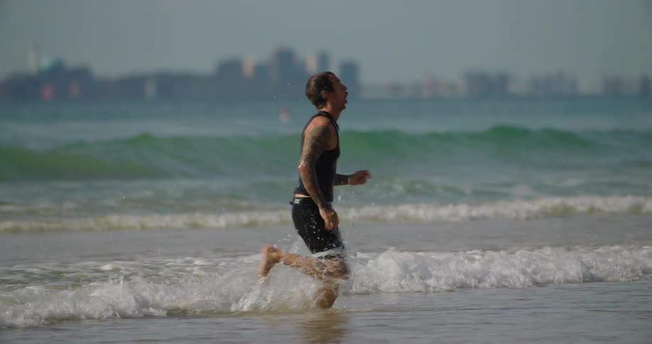 A man runs through the surf on a beach