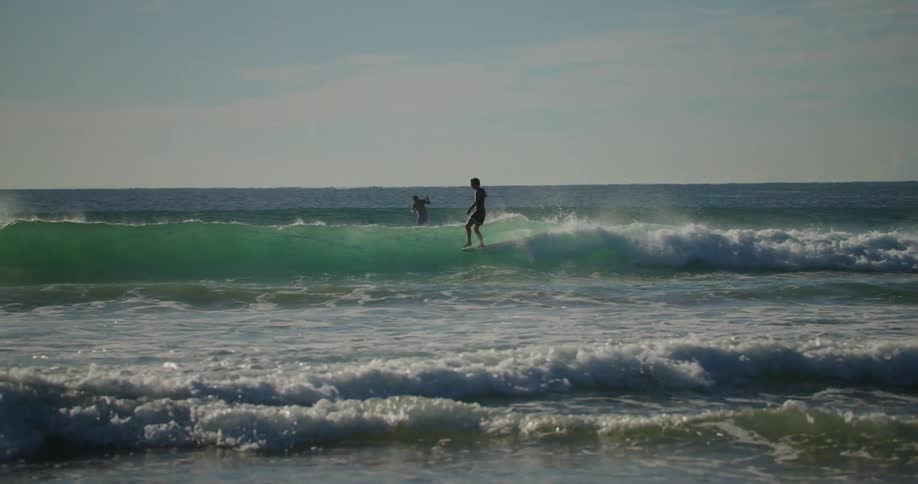 People surfing on the sea at sunset