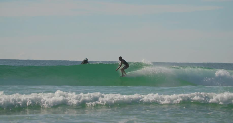Man riding a small wave with a longboard