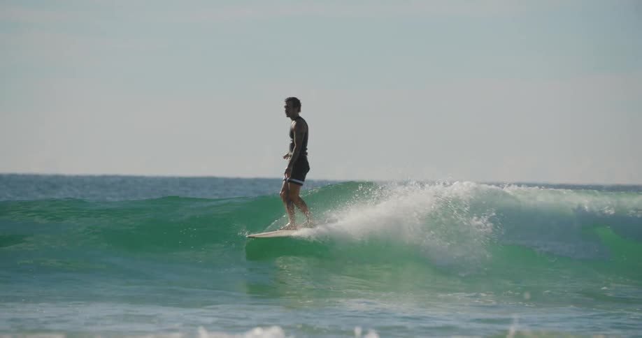 A man surfs a wave and fall off the board