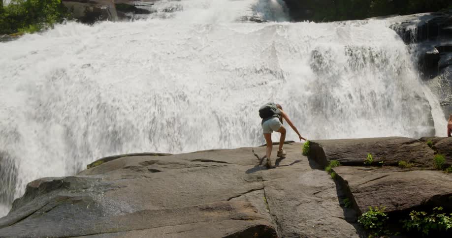 A woman climbs towards the waterfall