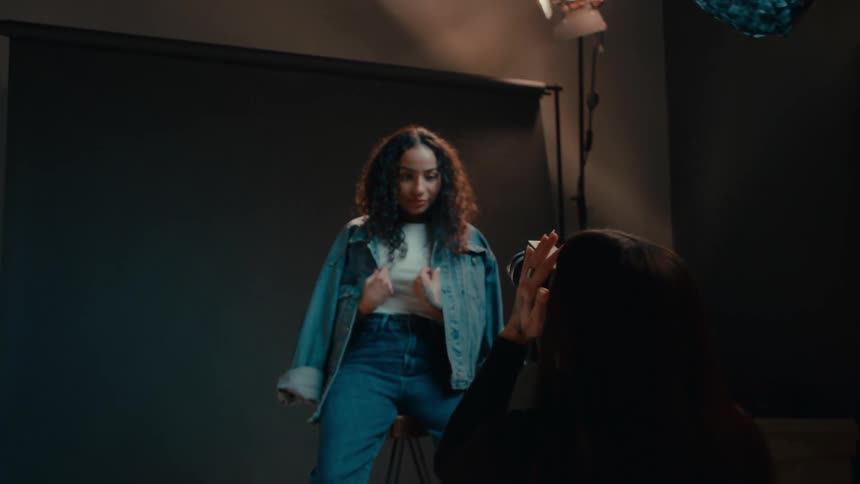 Model posing in denim clothes with a photographer in front of her