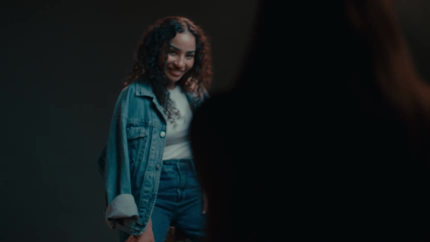 A black female models a denim jacket and laughs