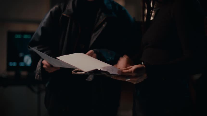 Two people stand and review several pages of paperwork together