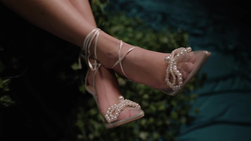 Closeup on the feet of a model wearing high heels with pearls